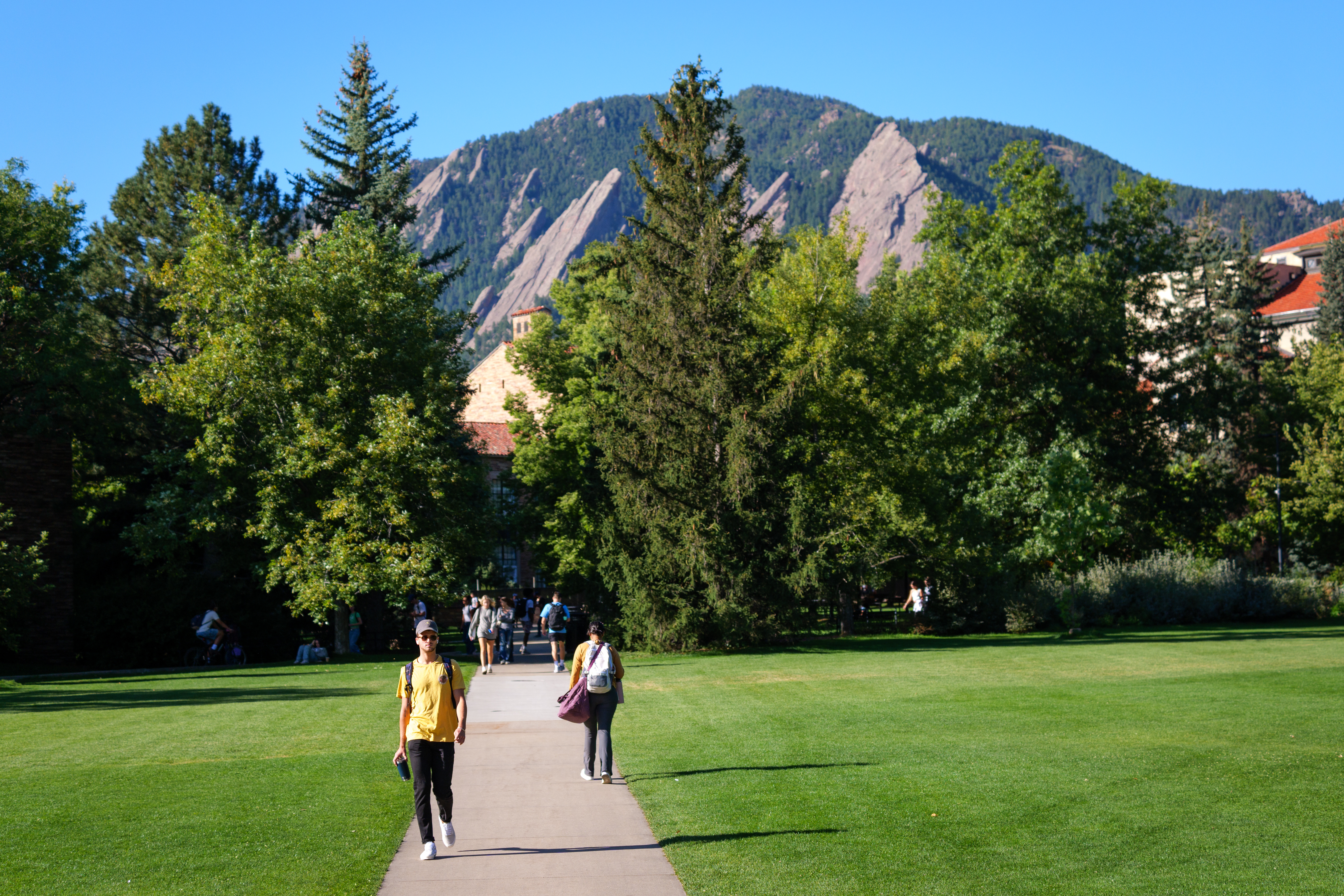Students walking through CU Boulder with the Flatirons in the background.